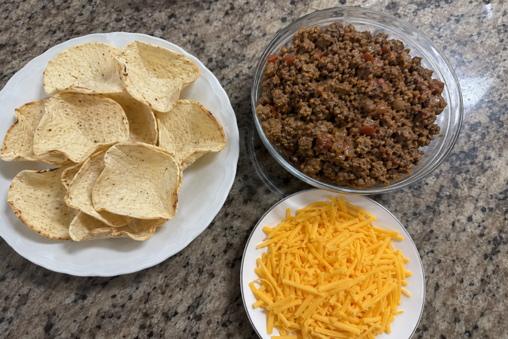 The three simple ingredients needed for easy BBQ snack bites corn cups, seasoned ground beef, and shredded cheddar cheese.